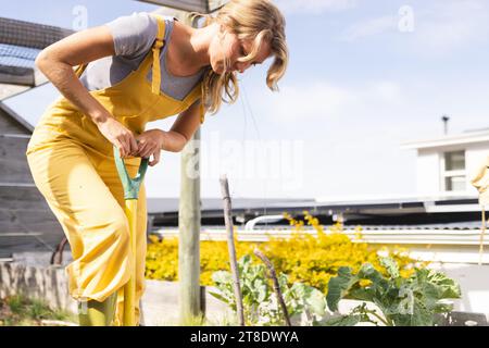 Happy blonde caucasian woman working in sunny garden Stock Photo