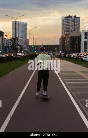 A young woman rides a longboard along the city streets. Stock Photo