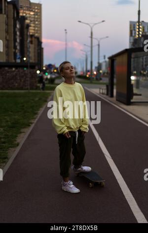 A young woman rides a longboard along the city streets. Stock Photo