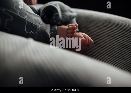 Close up side view of baby's feet and toes laying on gray neutra Stock Photo
