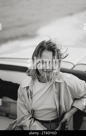 Young beautiful woman rides a speedboat on the lake. Wind in hair. Stock Photo