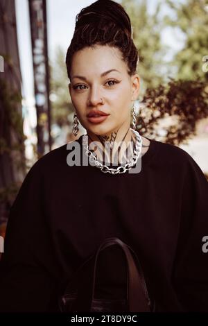 Beautiful young woman with a tattoo on her neck and dreadlocks. Stock Photo