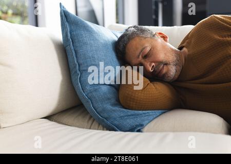 Senior biracial man lying on couch and sleeping at home Stock Photo