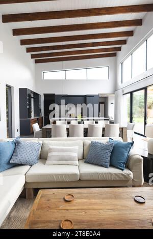 Big empty living room with wooden table, big white couch and pictures hanging on walls Stock Photo