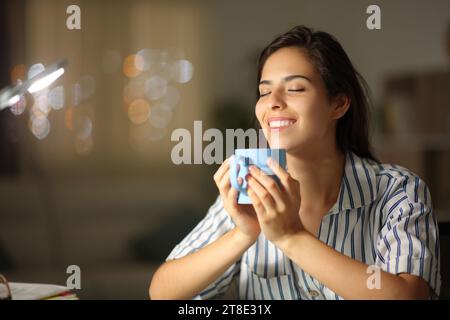 Happy woman drinking tea and breathing in the night at home Stock Photo