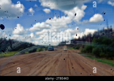 Dirty road after rain. Dirt highway with dirt flies on the windshield from other cars, dirty conditions for driver Stock Photo