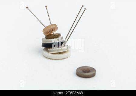 Horizontal photo, buttons stacked with pins, on white background, copy space. Concept hobbies and handicrafts. Stock Photo