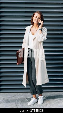 Stylish middle-aged woman wearing a coat talking on a mobile phone Stock Photo