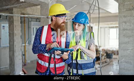 Man and woman builders using touchpad working at construction site Stock Photo