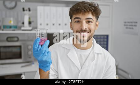 Confident arabian man happily working in science, a young smiling scientist, holding test tube in lab. a professional chemist conducting secure medica Stock Photo
