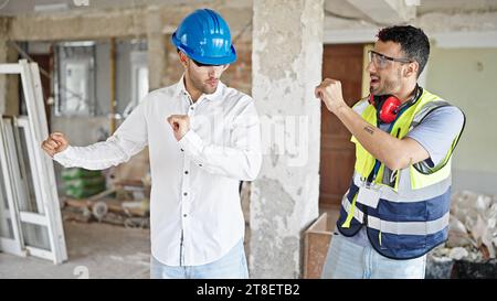 Two men builder and architect smiling confident dancing at construction site Stock Photo