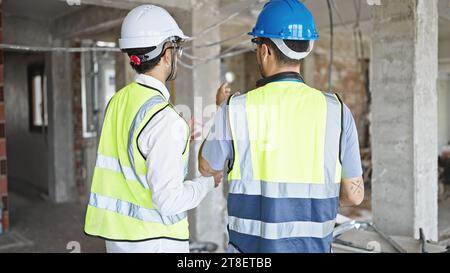 Two men builders standing backwards speaking at construction site Stock Photo