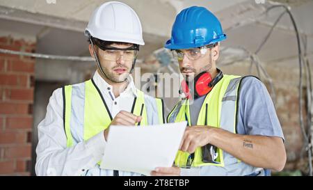Reading Builders Two men builders reading document speaking at construction site Stock ...