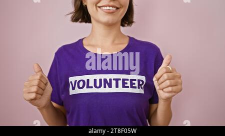 Enthusiastic young hispanic woman volunteer flashes confident thumb-up gesture, sporting short hair and charity uniform, grinning ear-to-ear isolated Stock Photo