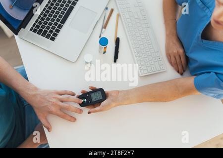 Diabetologist doctor testing blood sample on glucometer in diabetes clinic. Doctor taking blood sample from boy's finger. Paediatric diabetes in Stock Photo
