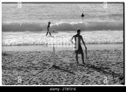 Teenagers play cricket on the beautiful sandy beach at Gwynver Beach at Sennen with a surf board as the stumps in Cornwall, England, August 2000. Picture: ROB WATKINS Stock Photo