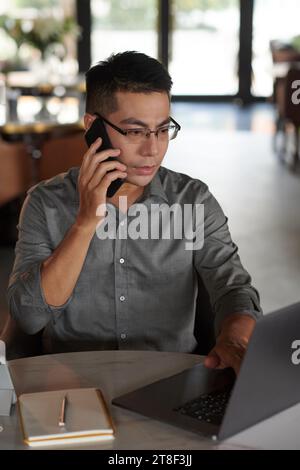 Businessman checking emails and making phone call to his colleague Stock Photo