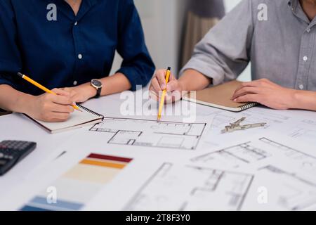 Two architects pointing on blueprint and analyzing about construction of building project together. Stock Photo