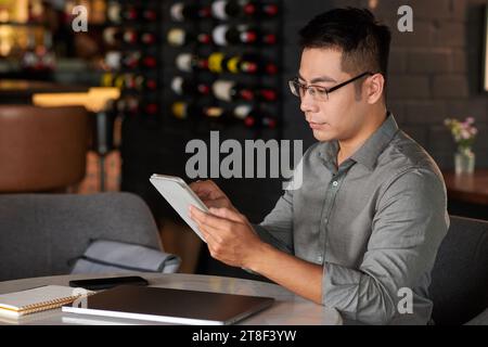 Businessman reading document on digital tablet when working at table in cafe Stock Photo