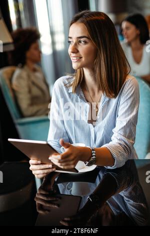 Young happy successful business woman working with tablet in corporate office Stock Photo