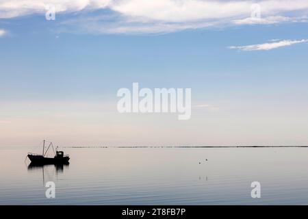 Silhouette of a traditional wooden fishing boat in a lagoon on Saaremaa island in Estonia Stock Photo