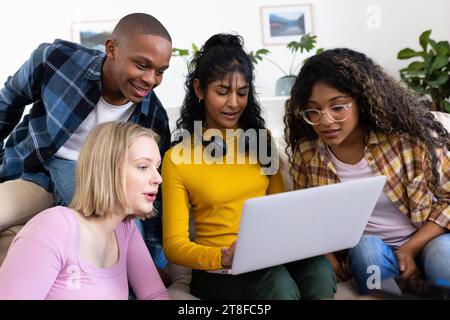 Happy diverse group of teenage friends using laptop at home Stock Photo