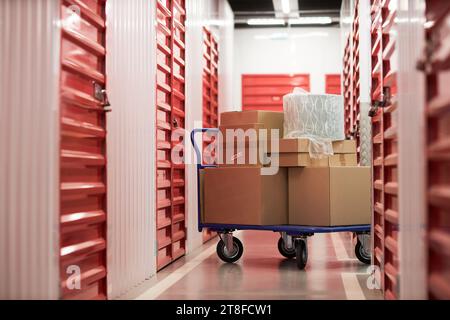 Cart with cardboard boxes in corridor of self-storage Stock Photo