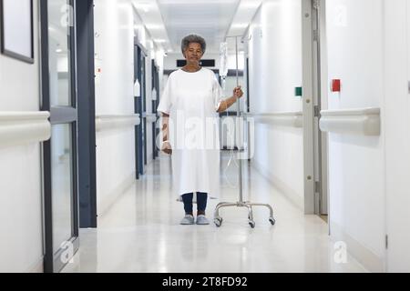 African american senior female patient with drip standing in hospital corridor Stock Photo