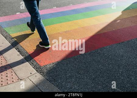 A person walking over a vibrant rainbow crossing on a sunny day in London, reflecting diversity and inclusivity. Stock Photo