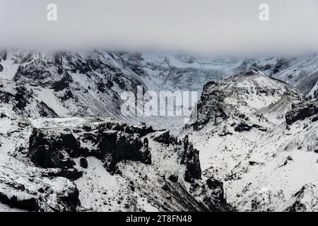 Aerial view of snow-covered mountain range with intricate patterns of rock and snow under a brooding sky Stock Photo