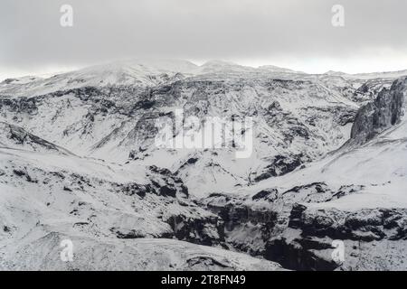 Aerial view of snow-covered mountain range with intricate patterns of rock and snow under a brooding sky Stock Photo