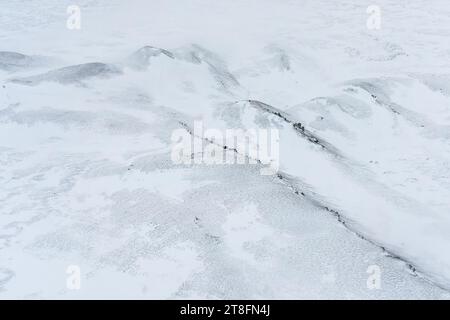 Aerial view of a snow-covered surface, showcasing the texture and subtle variations in a monochromatic winter landscape Stock Photo