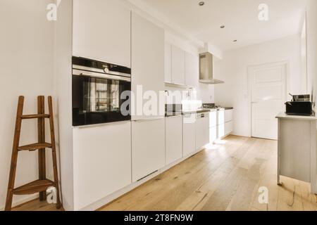 Interior of spacious kitchen with modern appliances and white cabinets in luxury light apartment Stock Photo