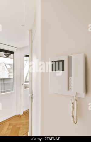 Intercom mounted on white wall by empty hallway in light contemporary house with closed doors Stock Photo