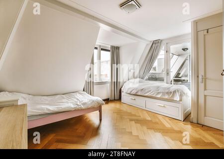 Interior of spacious bedroom with two comfortable beds in modern apartment with white walls and bright window Stock Photo