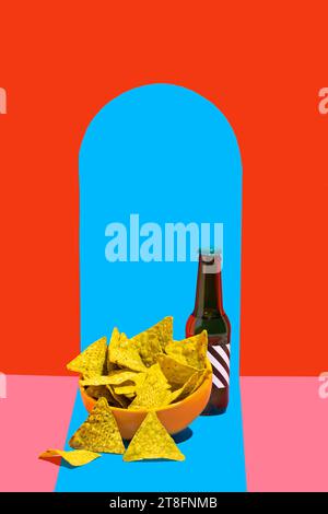 A vibrant still life image featuring a bowl of crunchy nacho chips beside a dark bottle against a split background of red and blue Stock Photo