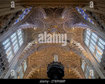 From below interior of Westminster Abbey church showcasing arches and vaults of its Gothic architecture with ornate chandeliers hanging from stone cei Stock Photo