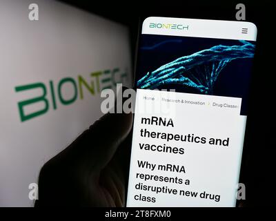 Person holding cellphone with webpage of German biotechnology company BioNTech SE in front of business logo. Focus on center of phone display. Stock Photo