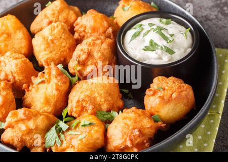 Southern Hush Puppies are light and flakey cornmeal dough that is fried golden brown on the outside and soft on the inside closeup on the plate on the Stock Photo