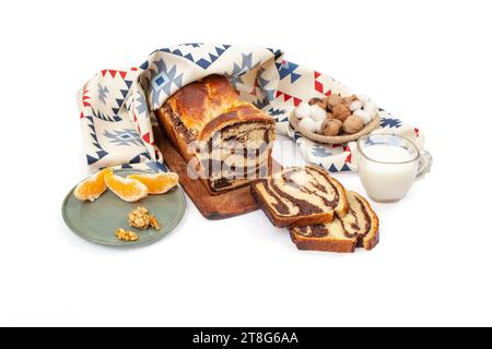 Cozonac, Romanian traditional sweet bread with walnut filling, sliced , with a glass of milk and patterned cloth, side view Stock Photo