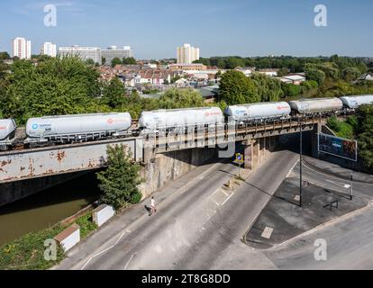 A freight train of tanker wagons crosses Feeder Road and the Feeder Canal in the industrial St Philip's Marsh area of Bristol, with the Barton Hill ne Stock Photo