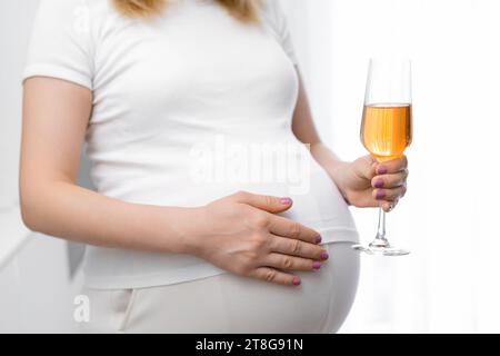 Close up glass of wine in pregnant womans hand. Alcohol during pregnancy Stock Photo