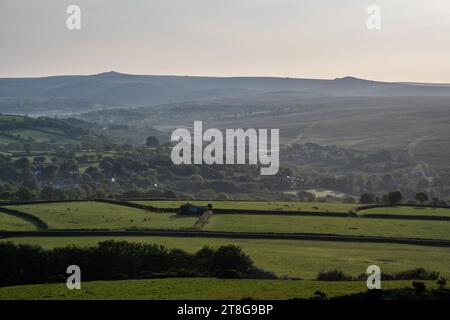 Morning light shines on the farmland and woods of the Lydford and North Brentor valleys under the hills and tors of Dartmoor in West Devon. Stock Photo
