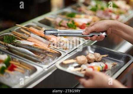 Hands of person taking various skewers from market stall Stock Photo