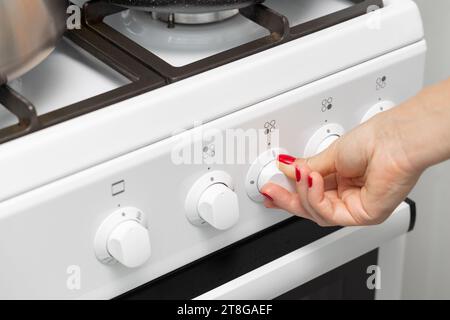 a woman's hand rotates the selector on a gas stove. woman's hand turns on the burner on a gas stove. High quality photo Stock Photo