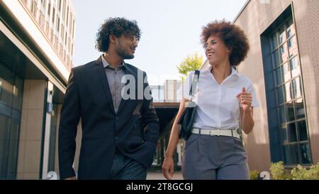 Two happy talking business colleagues business diverse multiracial coworkers Arabian businessman and African American businesswoman talking walking in Stock Photo