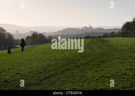 People walk through Stoke Park in north Bristol, with the skyline of the city centre, Kingsdown, St Michael's Hospital and the University of Bristol b Stock Photo