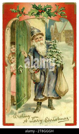 Original Victorian Christmas card - Father Christmas wearing a blue robe, bearing a sack of presents, carrying a Christmas tree, knocking at the door of a home where excited children wait for his arrival. circa 1905, U.K. Stock Photo