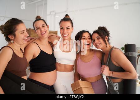 Group of beautiful sporty women smiling happily together in yoga class. Cheerful fitness friends. Stock Photo