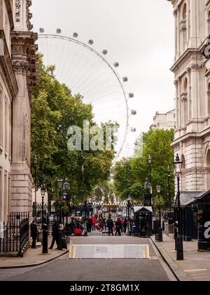 Police guard the gates of Downing Street, between the Cabinet Office and Foreign Office government buildings in London's Whitehall, with the London Ey Stock Photo